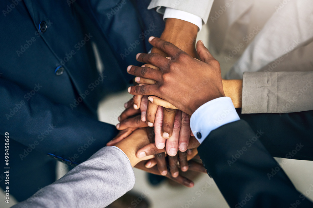 Poster bring it in, team. high angle shot of a group of unrecognizable businesspeople joining their hands t
