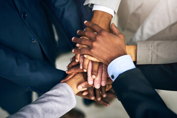 Bring it in, team. High angle shot of a group of unrecognizable businesspeople joining their hands...