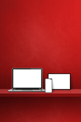 Laptop, mobile phone and digital tablet pc on red wall shelf. Vertical background