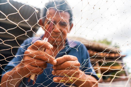 Close-up of a fisherman repairing a net to catch squid on a beach in Leon, Nicaragua. Concept of lifestyle of native ethnic groups in Latin America.