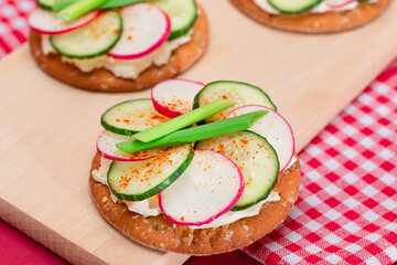 Light Breakfast or Diet Eating - Crispy Cracker Sandwich with Cream Cheese, Fresh Cucumber, Green Onions and Radish on Wooden Cooking Board on Magenta Background