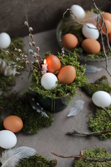 Easter holiday theme. Eggs, feathers, moss and thin twigs on the table. Happy easter 2022.