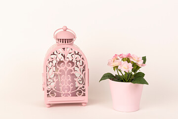 Farol rosa y macetero con flores rosas.