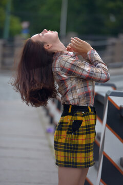 pretty brunette girl in a plaid blouse and skirt on a city street