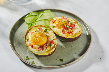 Avocado baked with egg, ham, tomatoes and cheese. Keto lunch recipe. After baking