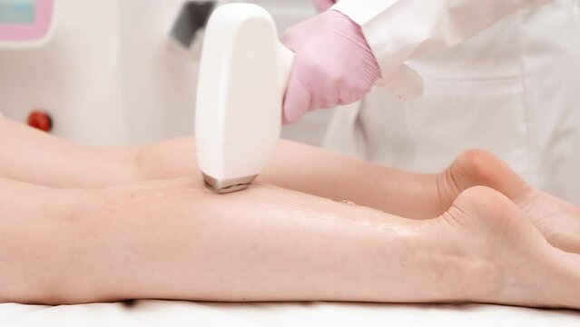 Flash of diode laser hair removal, Beautician removes hair on beautiful female legs, Hair removal for smooth skin, laser procedure at beauty studio or clinic, Body care epilation treatment.