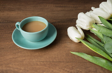 A cup of coffee and milk on the wooden table and white tulips