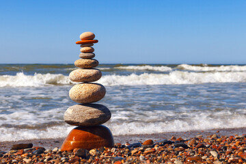 Zen pyramid of balanced stones on a background of the summer sea and blue sky