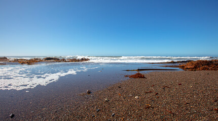 Tidal water emptying into Pacific Ocean at Moonstone Beach in Cambria on the Central California coastline in the United States