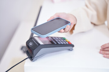 Spa customer paying with smartphone at reception desk