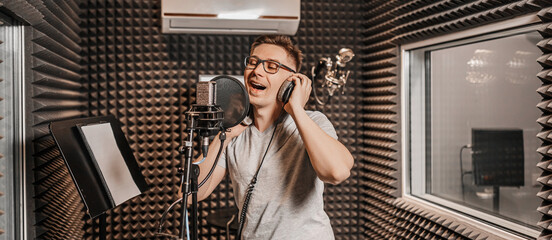 The vocalist sings in the studio in a microphone. Man in headphones writes a podcast, an audiobook. Artist, recording an album, working with the label. Announcer records a speech at a radio station