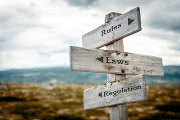 rules laws regulation text quote written in wooden signpost outdoors in nature. Moody theme feeling.