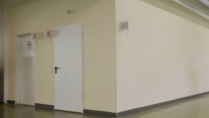 A washroom inside a shopping mall. HDR. Beige wall with white sign and silhouettes of man and woman...