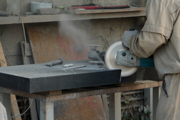 Man cuts a piece of black granite with a large grinder.