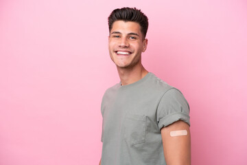 Young caucasian man wearing band-aids isolated on pink background smiling a lot