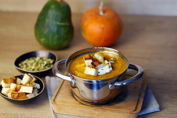Pumpkin soup in a saucepan with croutons.