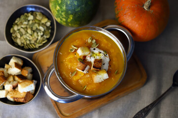 Pumpkin soup in a saucepan with croutons.