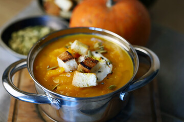 Pumpkin soup in a saucepan with croutons.