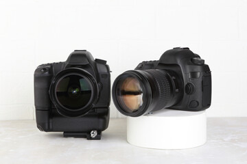Two Big Black DSLR Digital Camera full frame sensor with lens on gray white cement background.