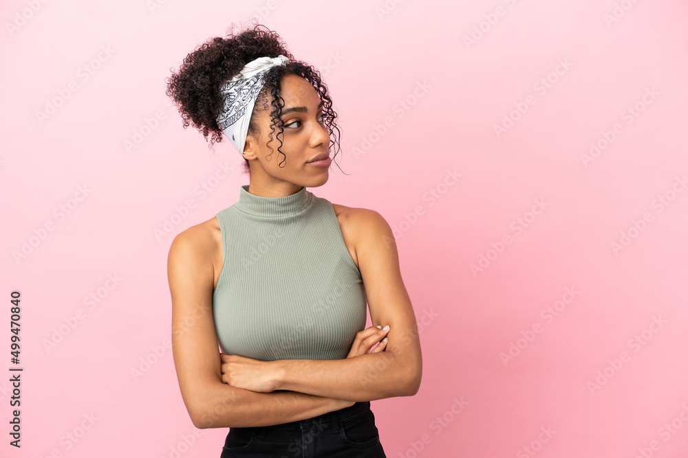 Sticker Young latin woman isolated on pink background looking to the side