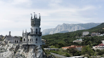 Aerial view of amazing Swallow's Nest at Gaspra in Crimea, Russia. Action. Fairytale castle built on the cliff top with green valley and blue sky on the background.