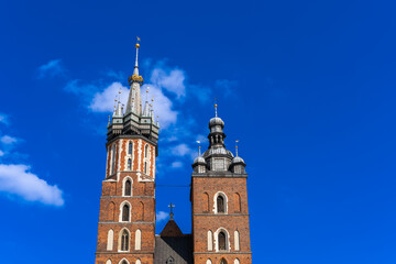 Fototapeta na wymiar Two Basilica Basilica Towers on Main Market Square Krakow On Sunny Day Under Blue Sky With White Clouds