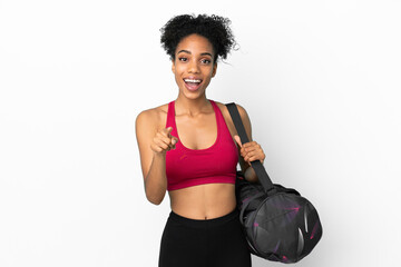Fototapeta na wymiar Young sport african american woman with sport bag isolated on blue background surprised and pointing front