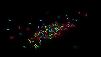 Colorful shining balls falling and rolling on a black background. Design. Many black children toy balls with neon lights falling on the floor.