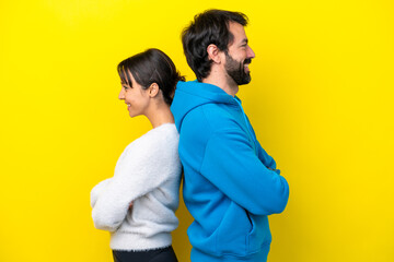 Young caucasian couple isolated on yellow background keeping arms crossed