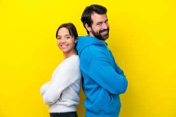 Obraz premium Young caucasian couple isolated on yellow background keeping arms crossed