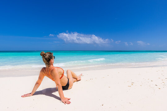 Young sexy woman relax on the beach. Perfect tropical island, beach shore, with turquoise ocean lagoon. Bikini, long legs, sunglasses enjoying summer vacation. Carefree woman beach portrait, leisure 