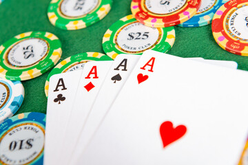 Closeup of four aces sitting on a pile of poker chips.