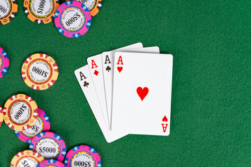 Four aces sit on a gaming table near a pile of poker chips. 