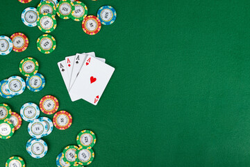 Four aces sit on a gaming table near a pile of poker chips. Copy space is available to the right of the subject. 