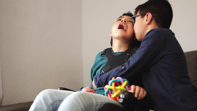 Child having tender moment with his brother with disability in wheelchair - Family love concept