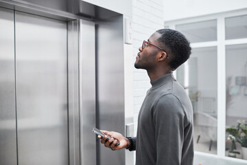 Naklejka na ściany i meble Minimal side view of young black businessman waiting for elevator in office building and holding phone, copy space