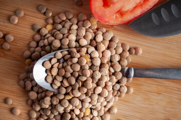 Macro photography, raw or uncooked lentils on a spoon and over a cutting board, top view overhead or flat lay shot