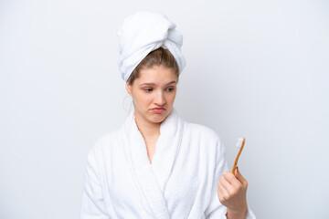 Teenager Russian girl brushing teeth isolated on white background with sad expression