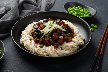 Jajangmyeon, black bean noodles in a black ceramic plate , selective focus