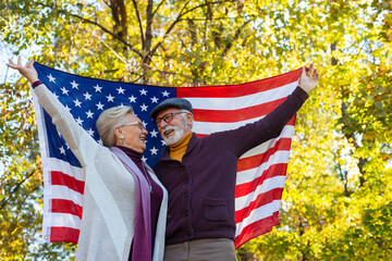 Senior couple holding american flag outdoors - Powered by Adobe