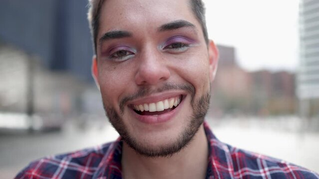 Gay man wearing making makeup smiling at camera outdoor - Non-binary and LGBT pride concept