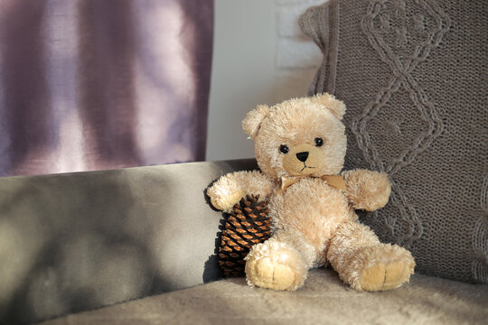 Plush toy teddy bear sits on a sofa
