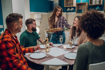 Group of friends enjoying dinner while sitting at the kitchen table together