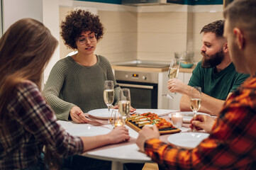 Group of friends enjoying dinner while sitting at the kitchen table together