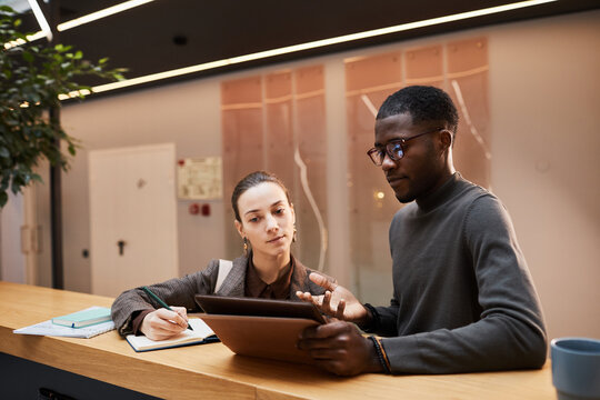 Portrait Of Black Young Businessman Talking To Female Colleague While Discussing Workin Hall At Modern Office Building