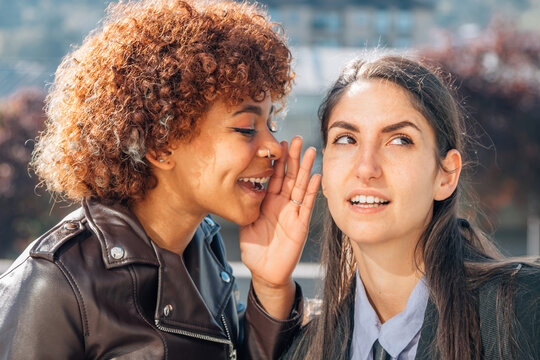 girl gossiping or whispering a secret in her friend's ear