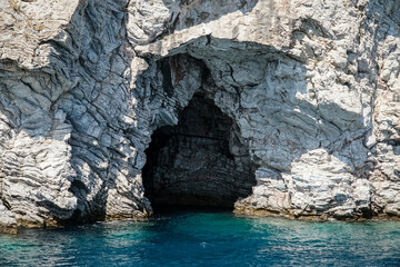 Cave. Entrance to the sea cave. Blue, clear water against the rocks backdrop 