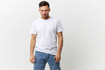Fototapeta premium Serious angry young tanned handsome man in basic t-shirt look at camera posing isolated on over white studio background. Copy space Banner Mockup. People emotions Lifestyle concept