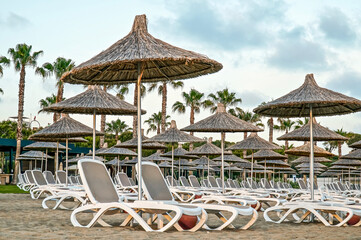 Umbrellas and sun beds on the sandy beach. Summer holiday concept for tourism, selective focus