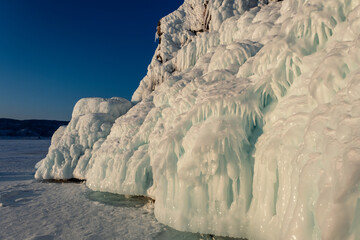 Ice and icicles on the rocks on Lake Baikal at frosty winter sunset